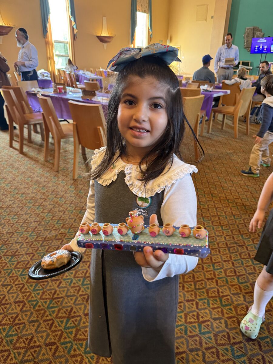 Academy student holding a decorated menorah at a community event