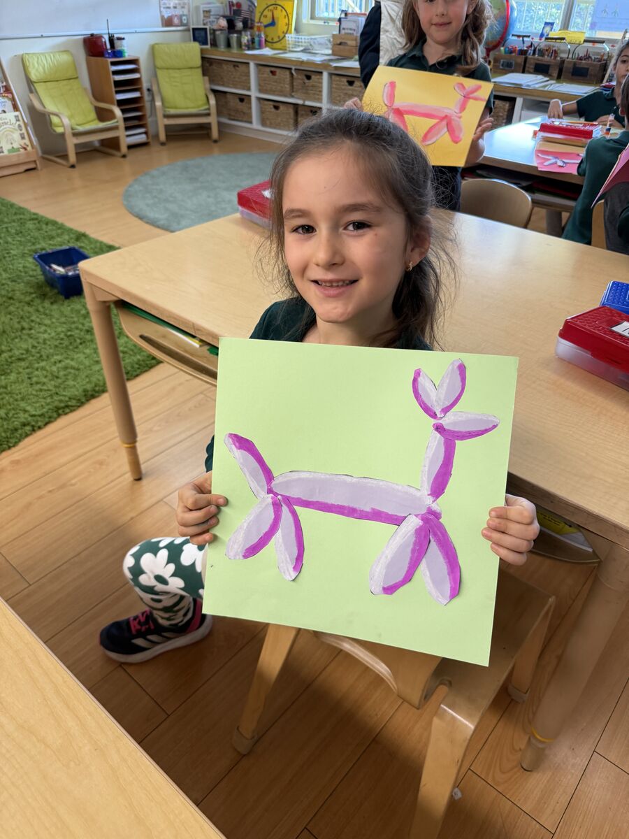 Student proudly holding a painting in the classroom